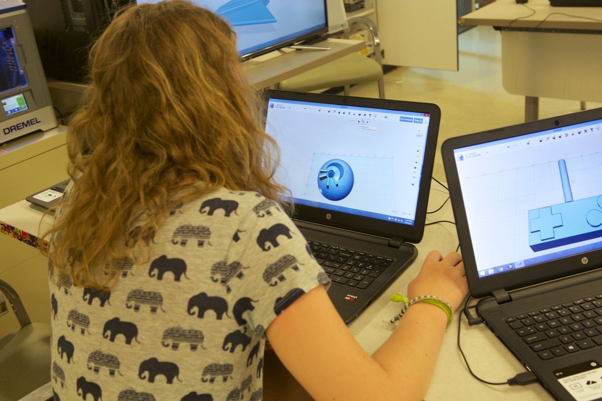A student designing a 3D model on a laptop