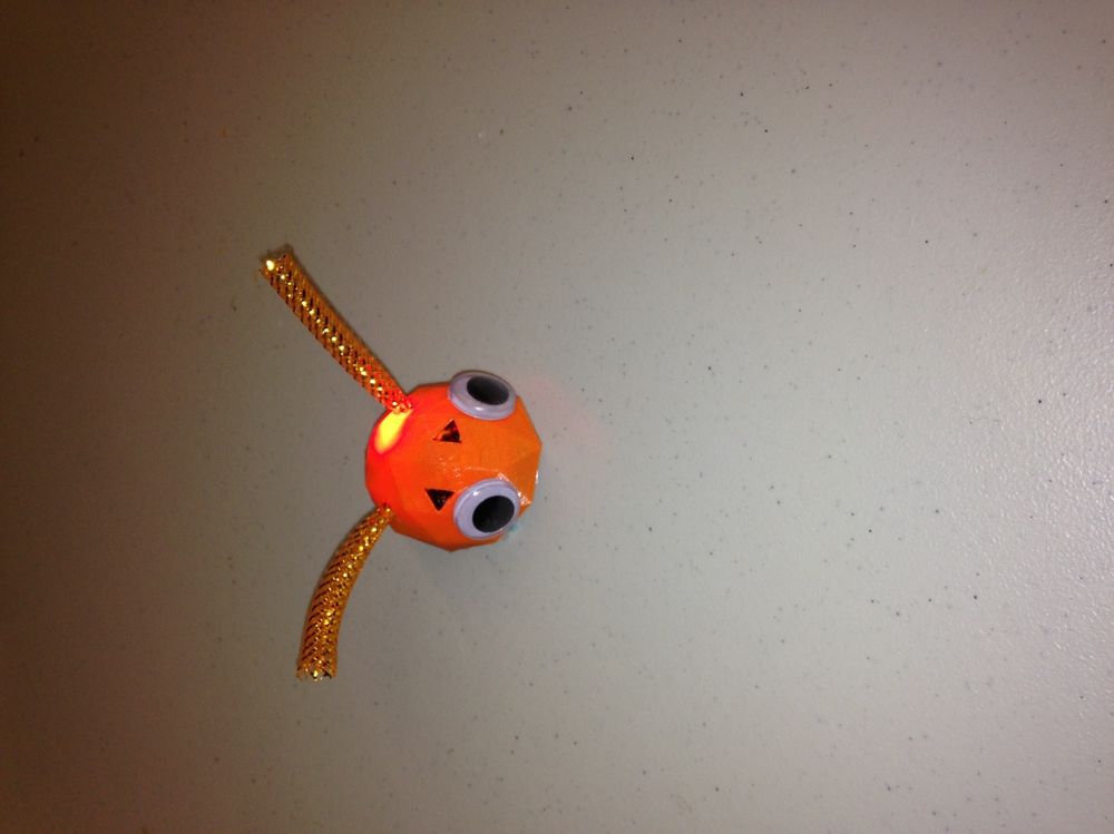 A PicoBot robot with bright orange shell and wire antennae